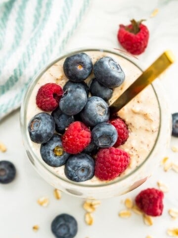 A jar of overnight oats with protein powder topped with fresh berries.