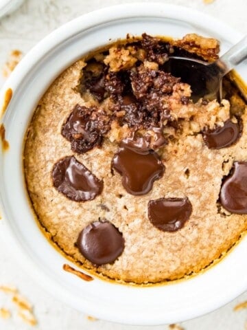 A bowl of protein baked oats topped with melted chocolate with a spoon in it.