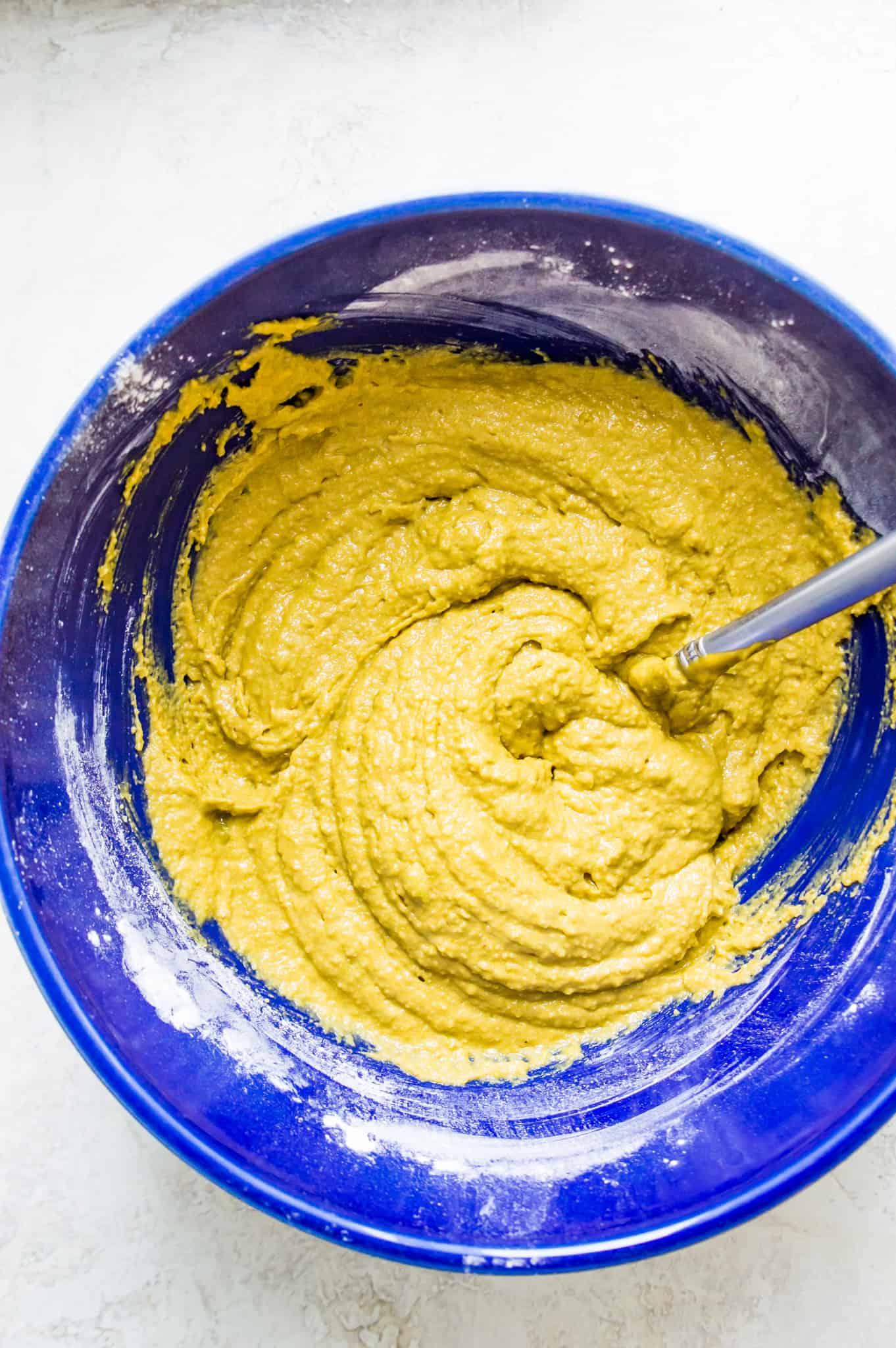 A bowl filled with bread batter with a spoon in the batter.