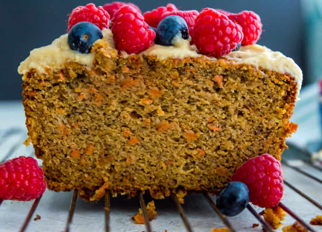 A piece of carrot cake banana bread with blueberries and raspberries on top.