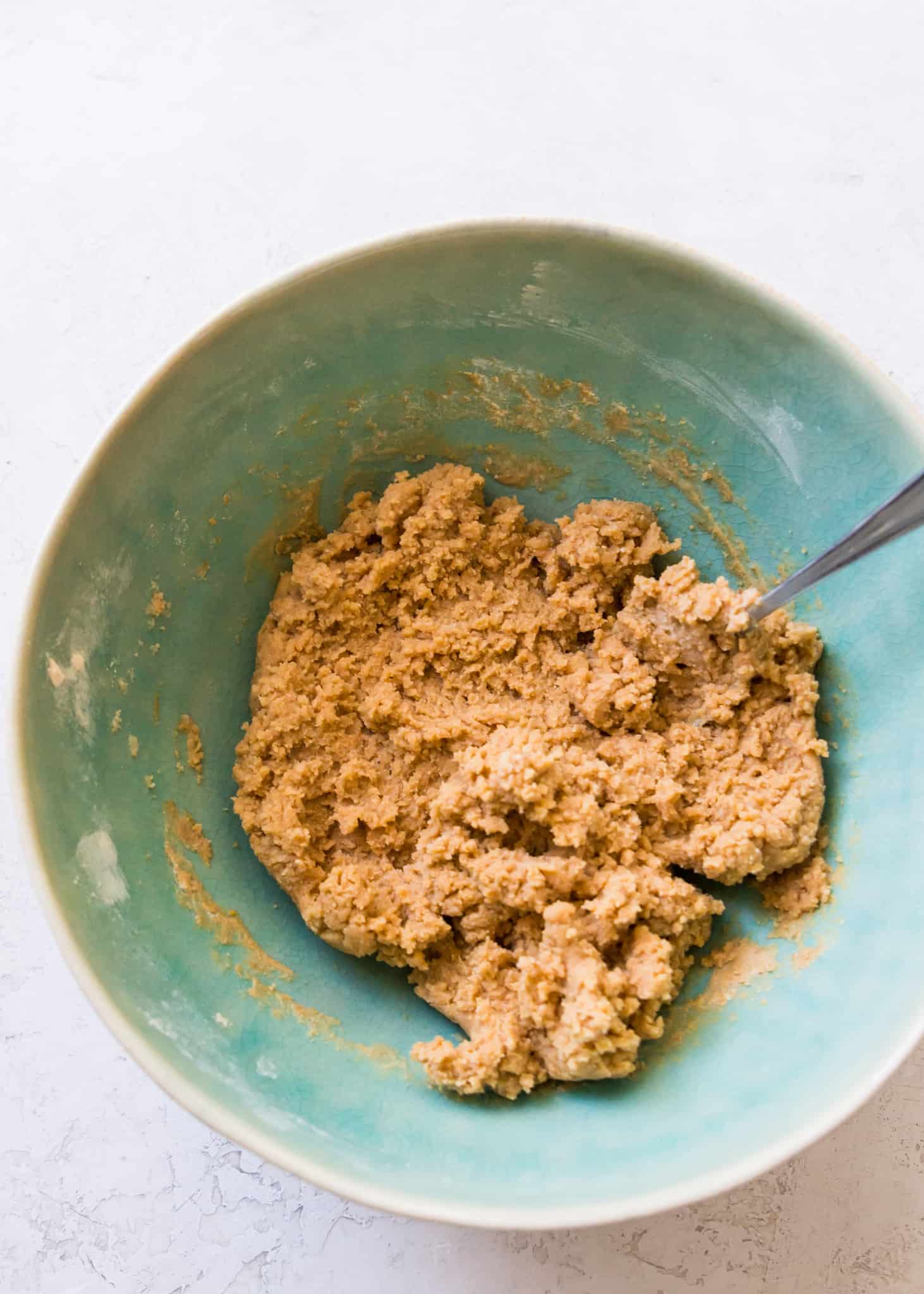 A bowl of edible cookie dough with a spoon in it.