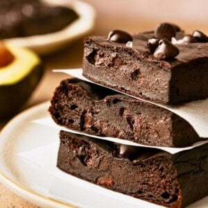 A stack of three avocado brownies topped with chocolate chips on a plate.