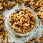 A jar full of grain free granola surrounded by granola pieces.