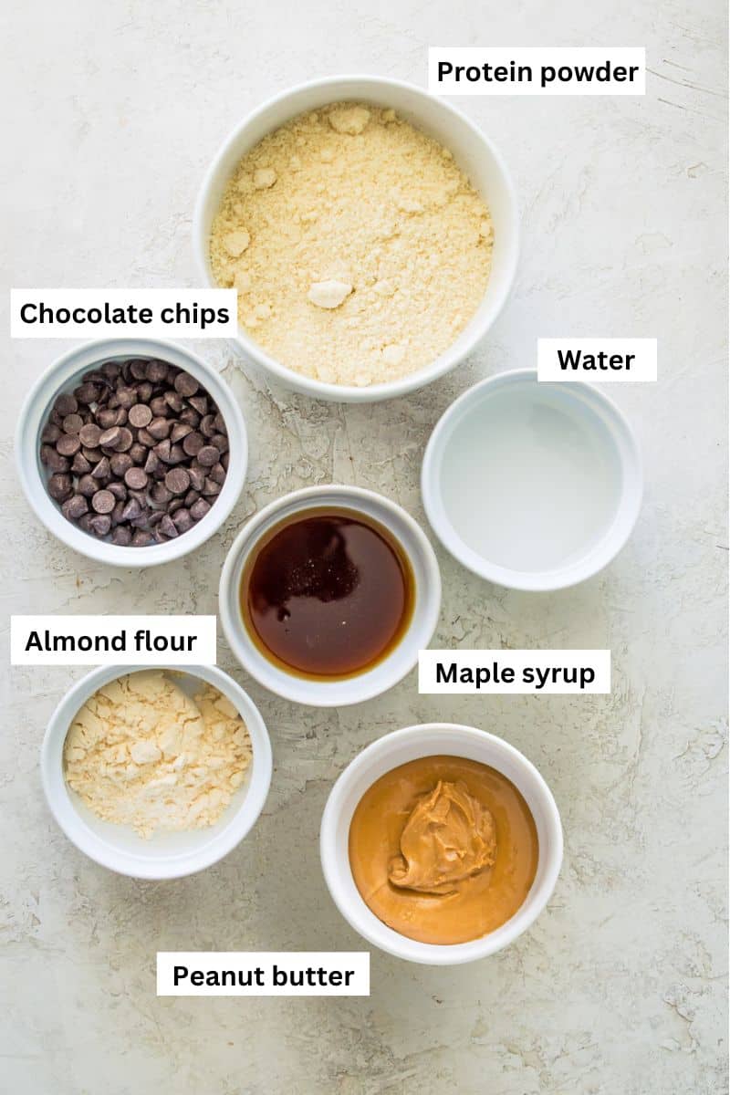 Bowls filled with different foods including chocolate chips, protein powder, almond powder, water and maple syrup.