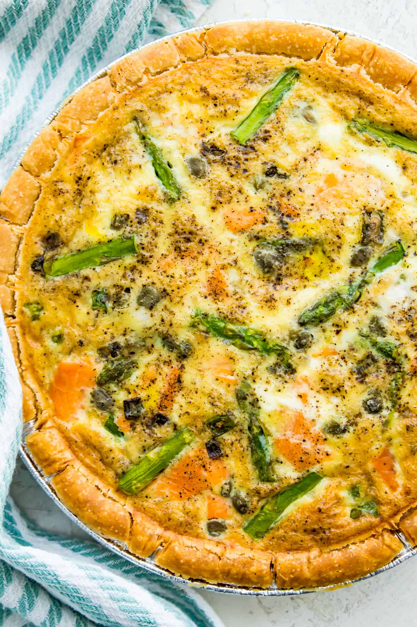 Close up on a baked quiche with asparagus and smoked salmon on a table. 