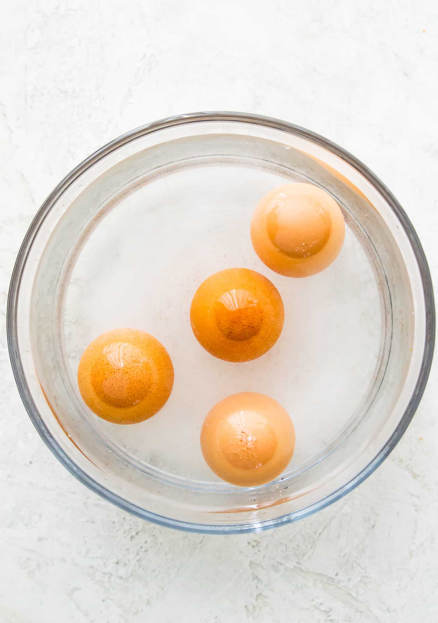 A glass bowl filled with water and four eggs.