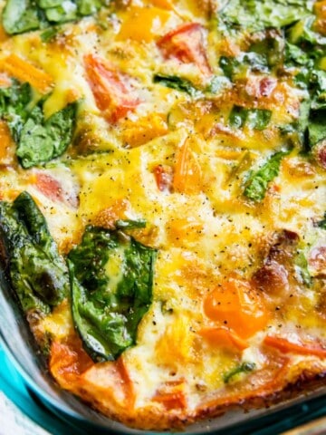 A glass dish filled with a bacon and vegetable egg casserole.
