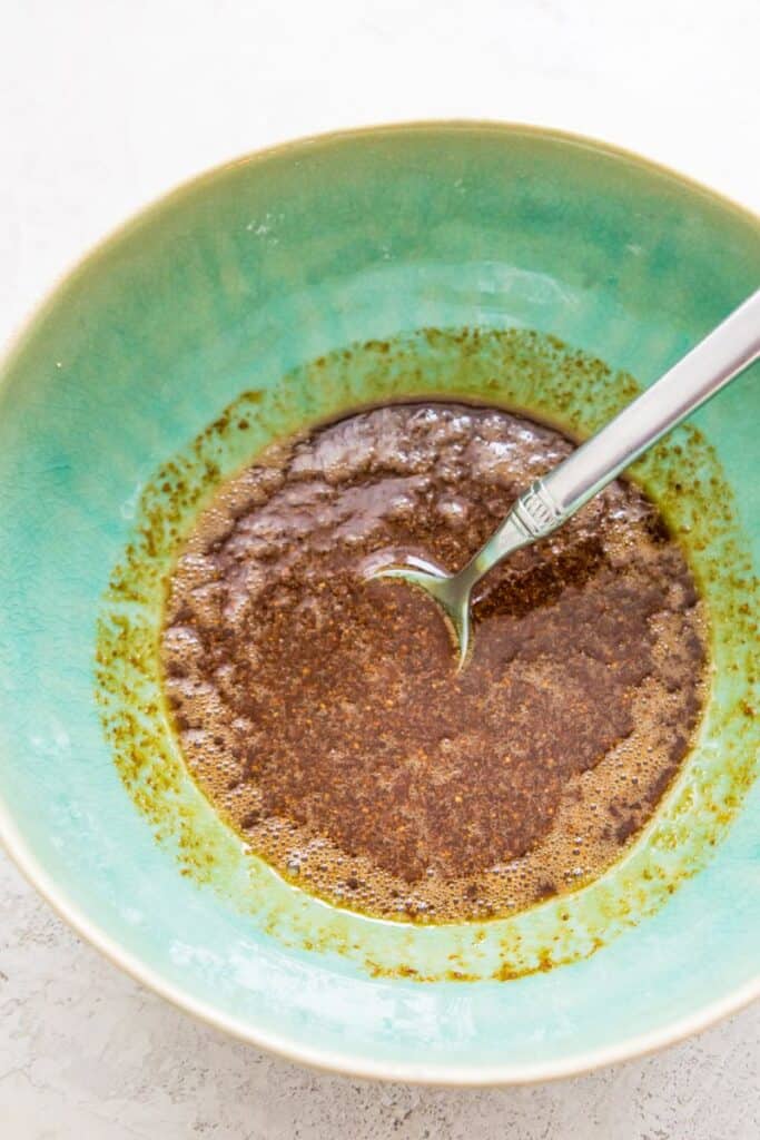 A bowl filled with a brown sugar liquid mixture with a spoon in it.