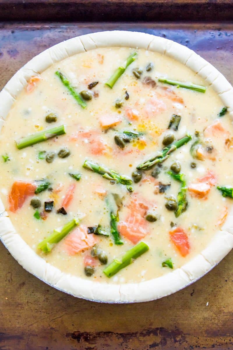 A pie crust filled with whisked eggs, chopped asparagus and chopped smoked salmon.