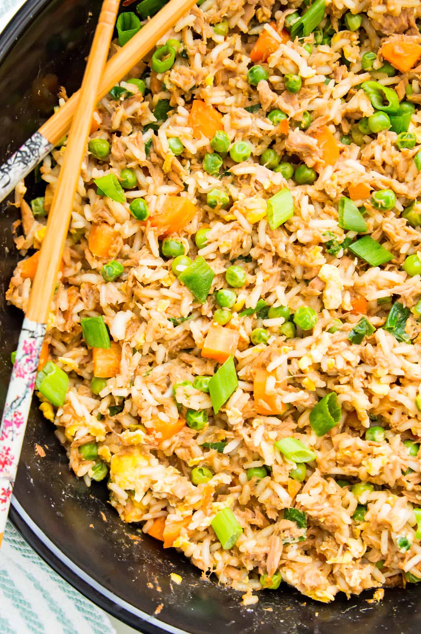 A pan of fried rice with tuna with chopsticks on top of it.