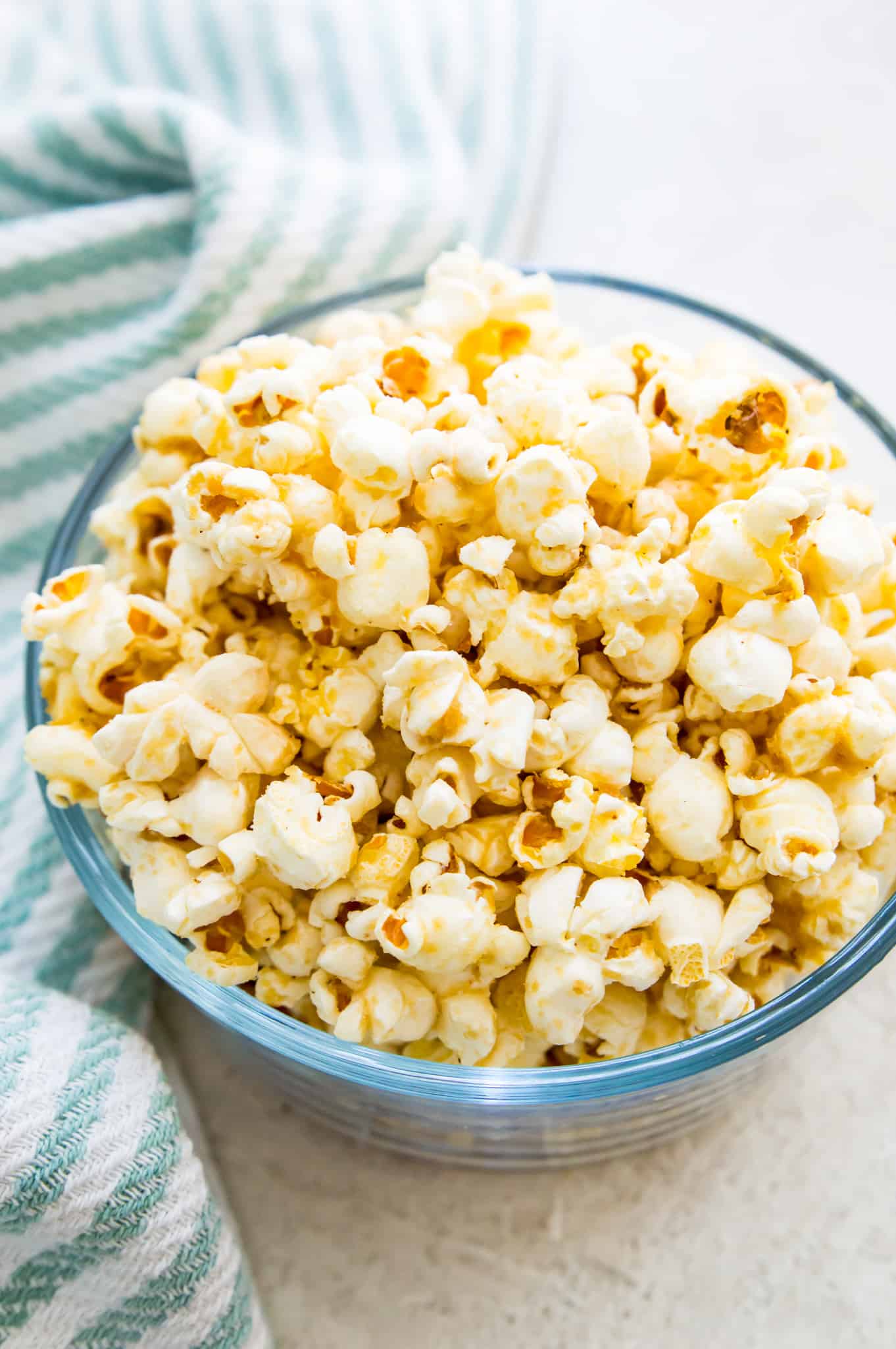 A bowl of vegan popcorn with a tea towel beside it.