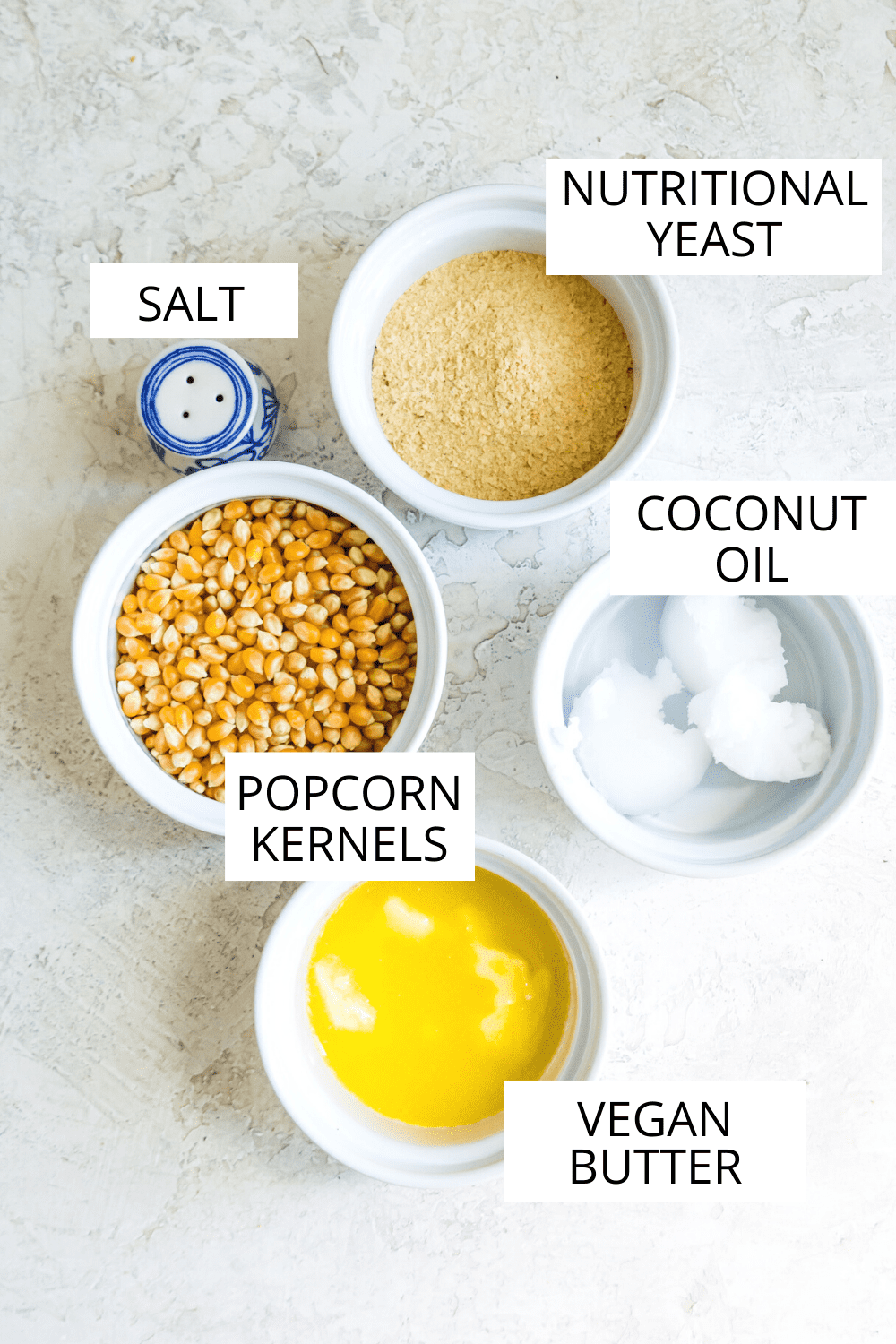 The ingredients needed for making vegan popcorn separated into small bowls. 