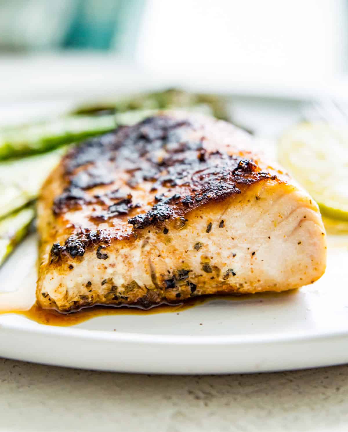 A piece of cooked blackened fish on a plate. 