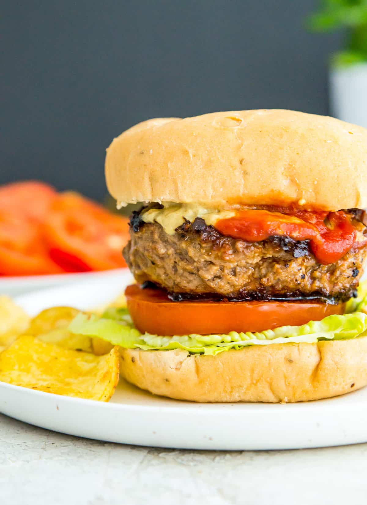 A gluten free burger on a bun topped with lettuce and tomato