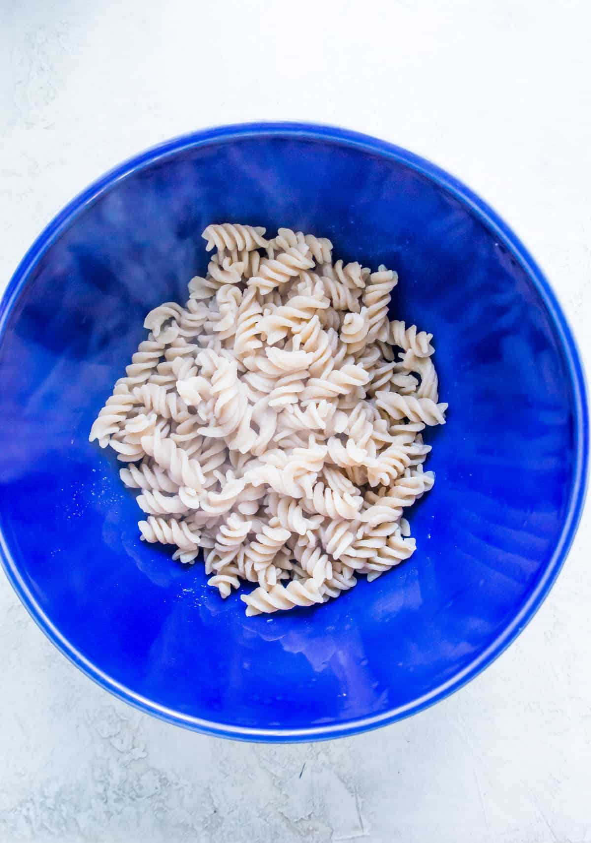 A large bowl filled with cooked spiral noodles.
