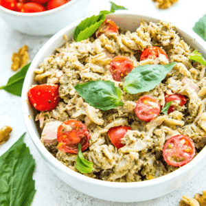 A bowl of tuna pasta pesto topped with fresh basil.