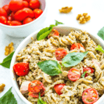 a bowl of tuna pesto pasta topped with fresh basil leaves