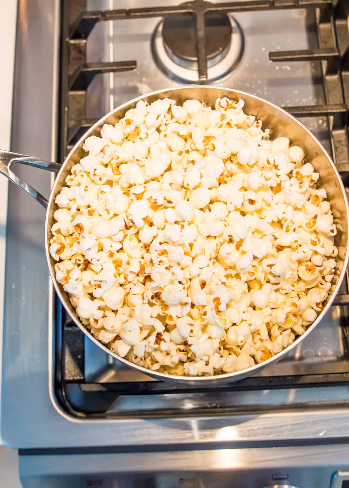 A pot on the stovetop filled with popcorn.
