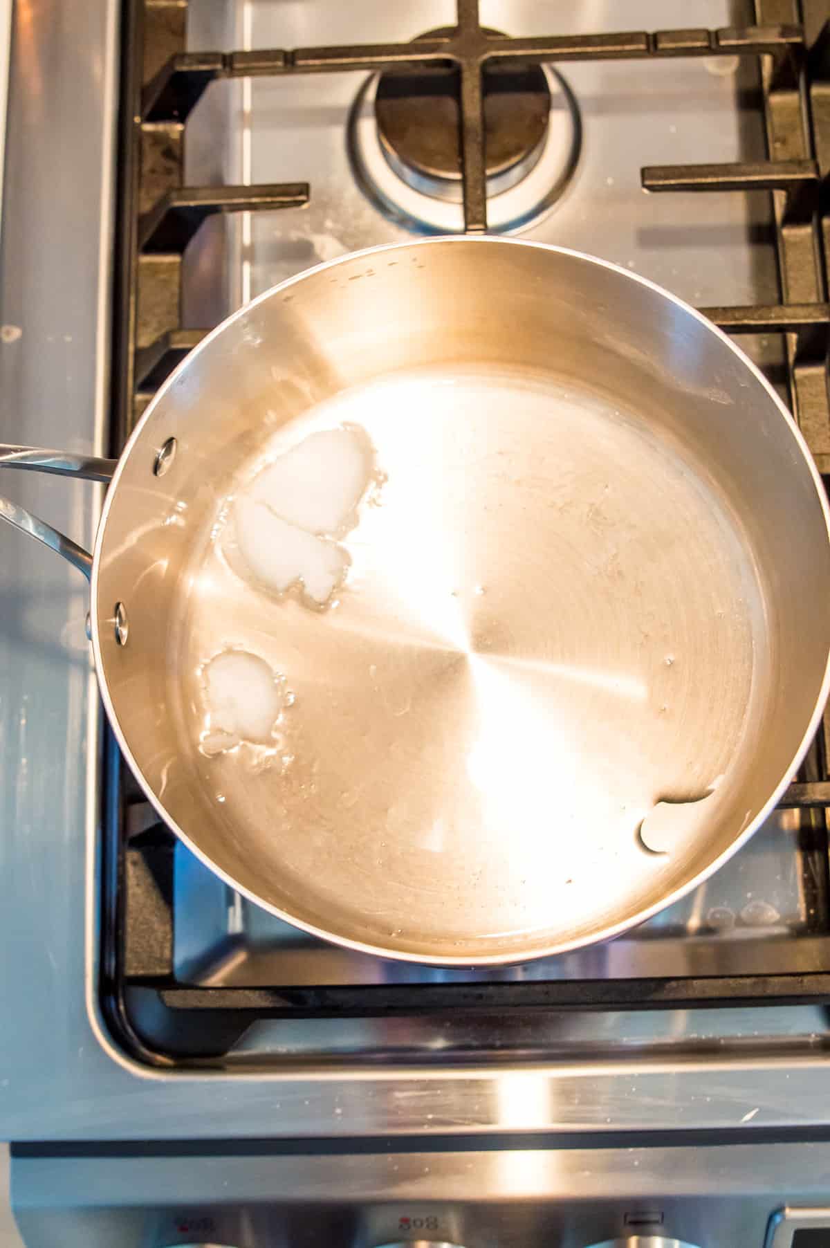 A pot on the stovetop with melted coconut oil in it.