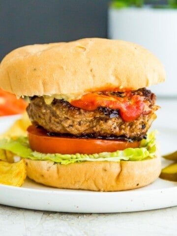 A gluten free burger in a bun with lettuce, tomato and ketchup.