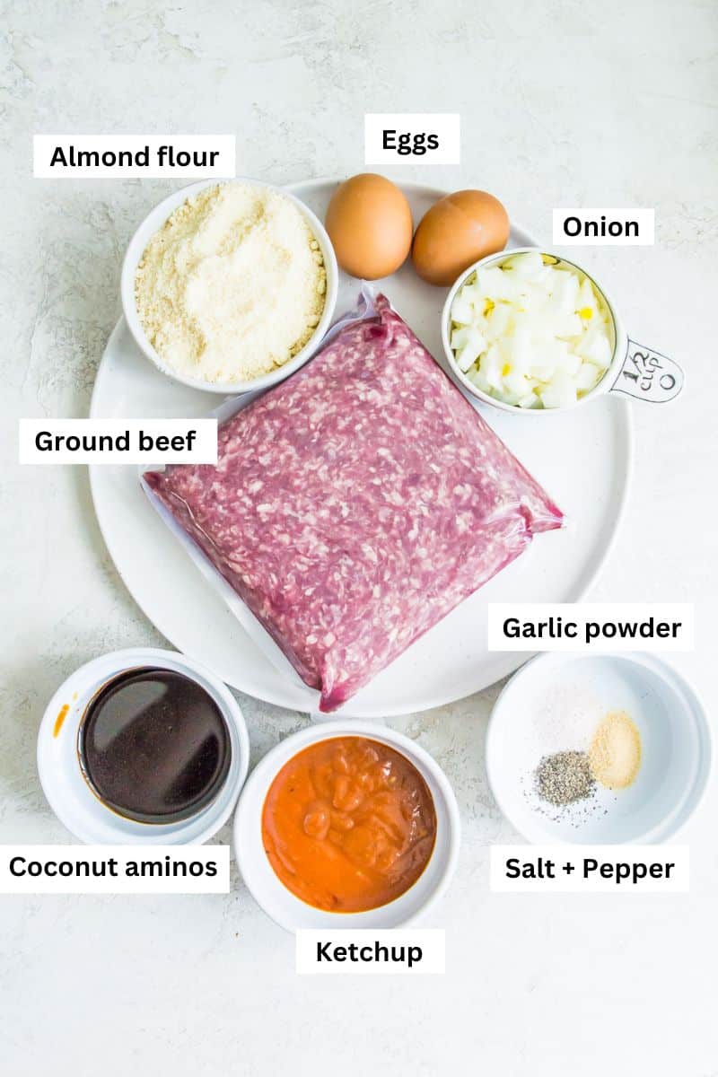 The ingredients for making gluten free burgers including ground beef, chopped onion, eggs, almond flour and ketchup.
