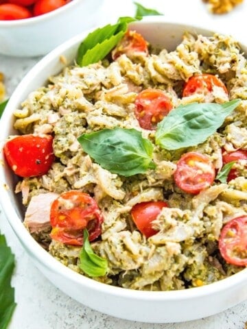 A bowl of tuna pasta pesto topped with fresh basil.