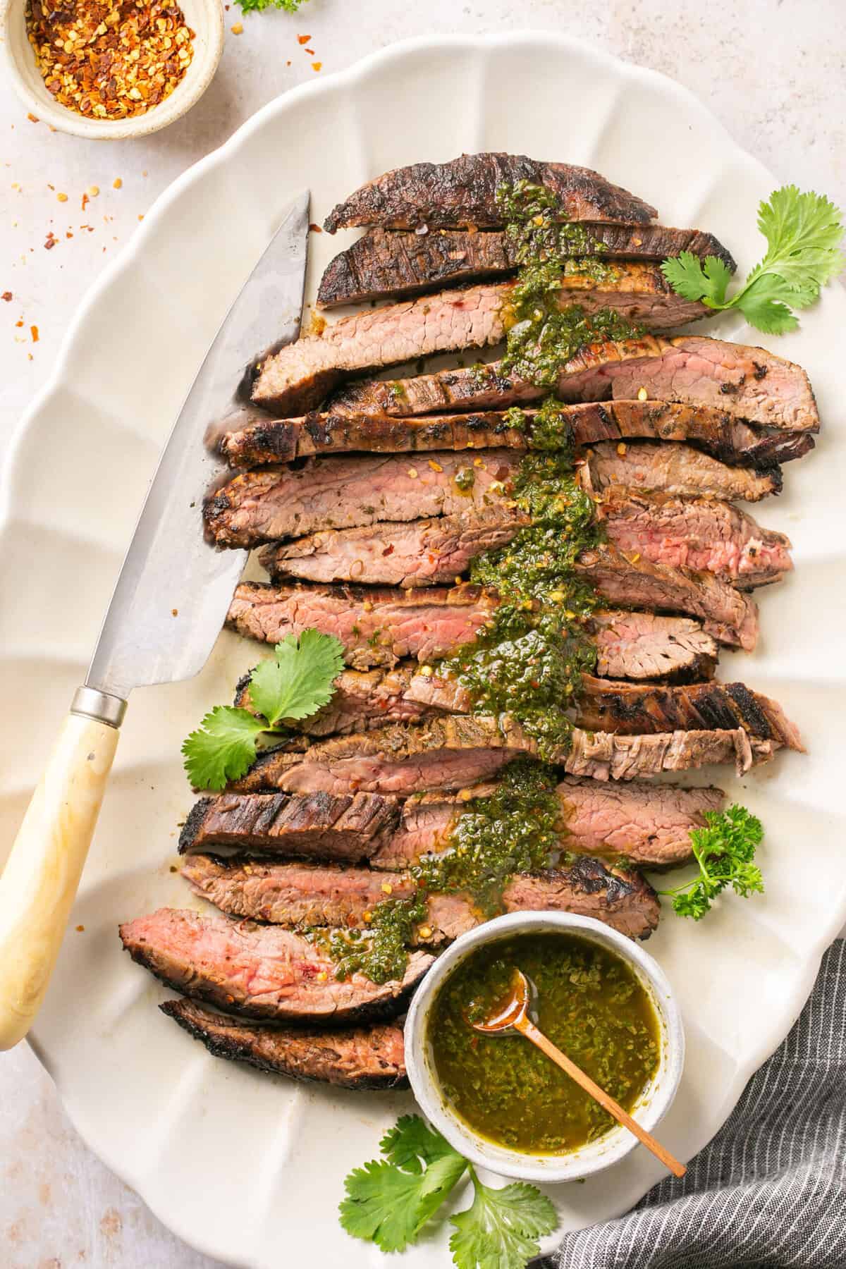 A steak cut into pieces topped with a chimichurri sauce.