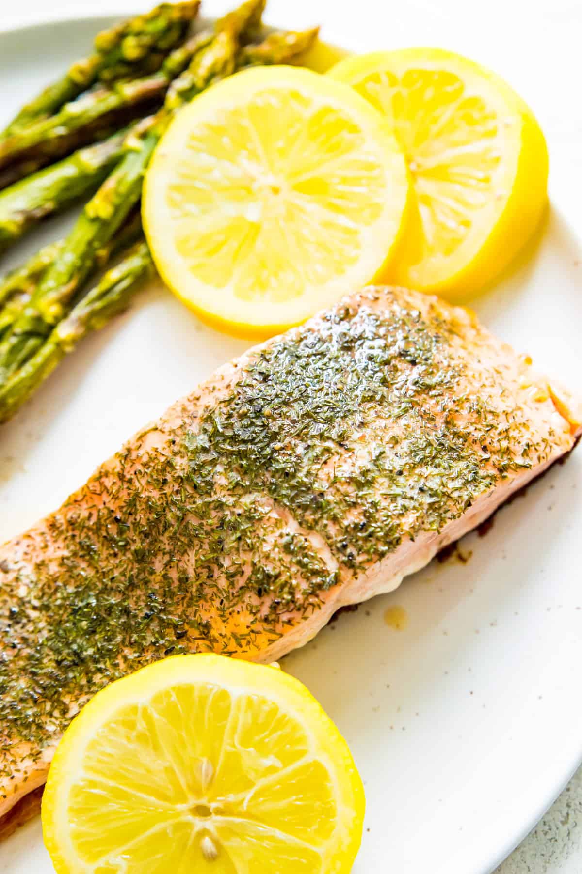 A piece of Faroe Island Salmon on a plate with asparagus and lemon slices.