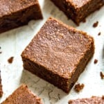 A batch of condensed milk brownies that have been cut into pieces with some brownie crumbs around them.