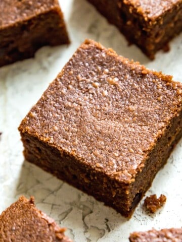 A batch of condensed milk brownies that have been cut into pieces with some brownie crumbs around them.