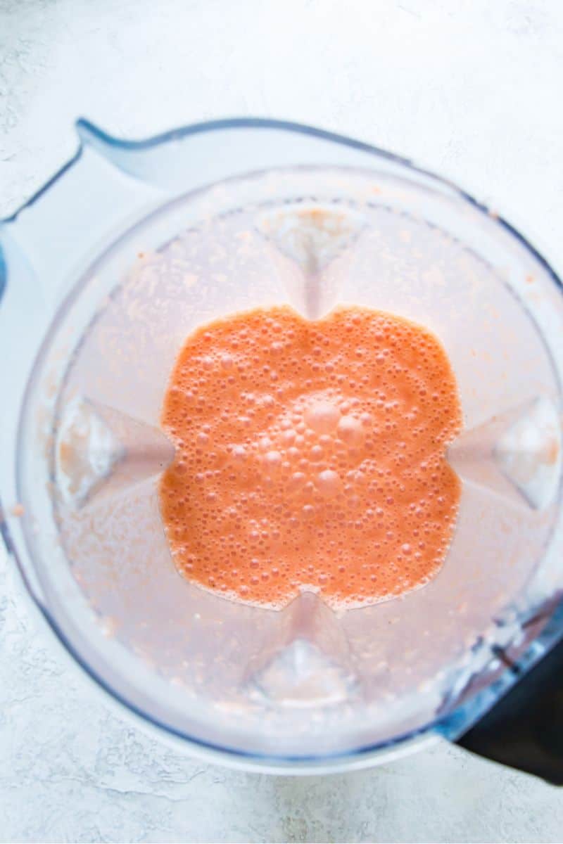 A blender with a pink smoothie in it.