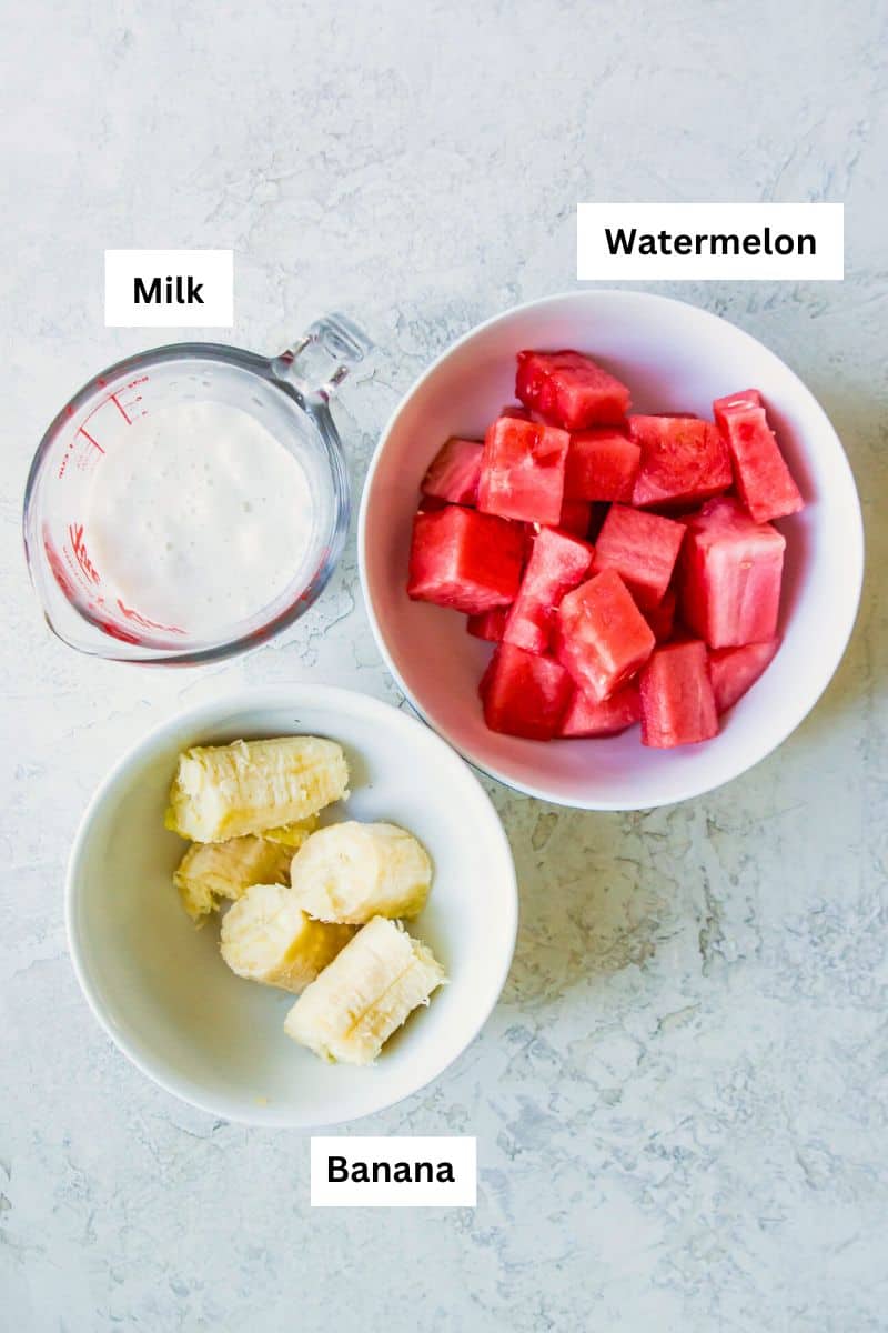 Three bowls, one with banana, one with watermelon and one with milk in it.