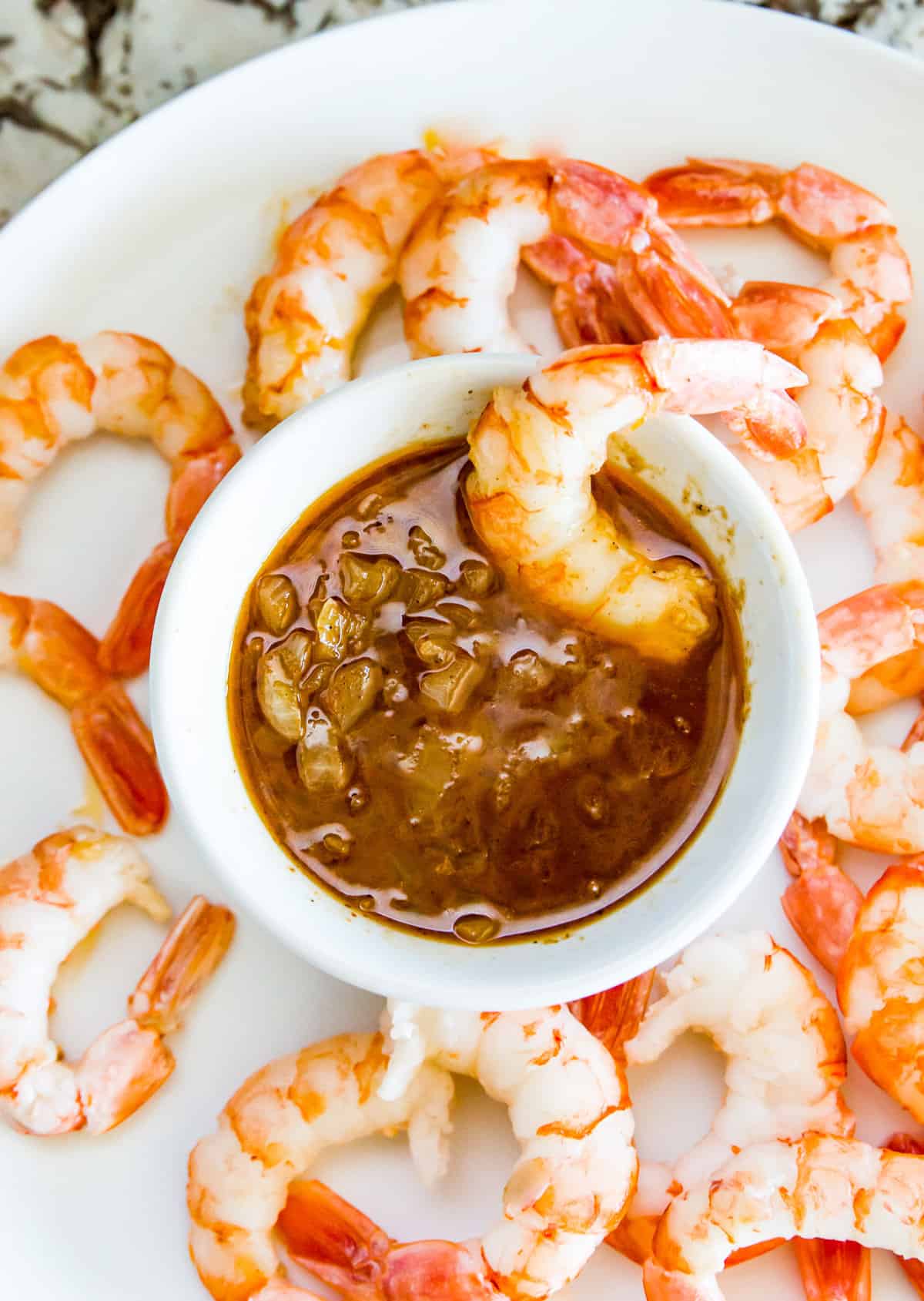 A shrimp in a bowl of cajun butter sauce with more shrimp surrounding the bowl.