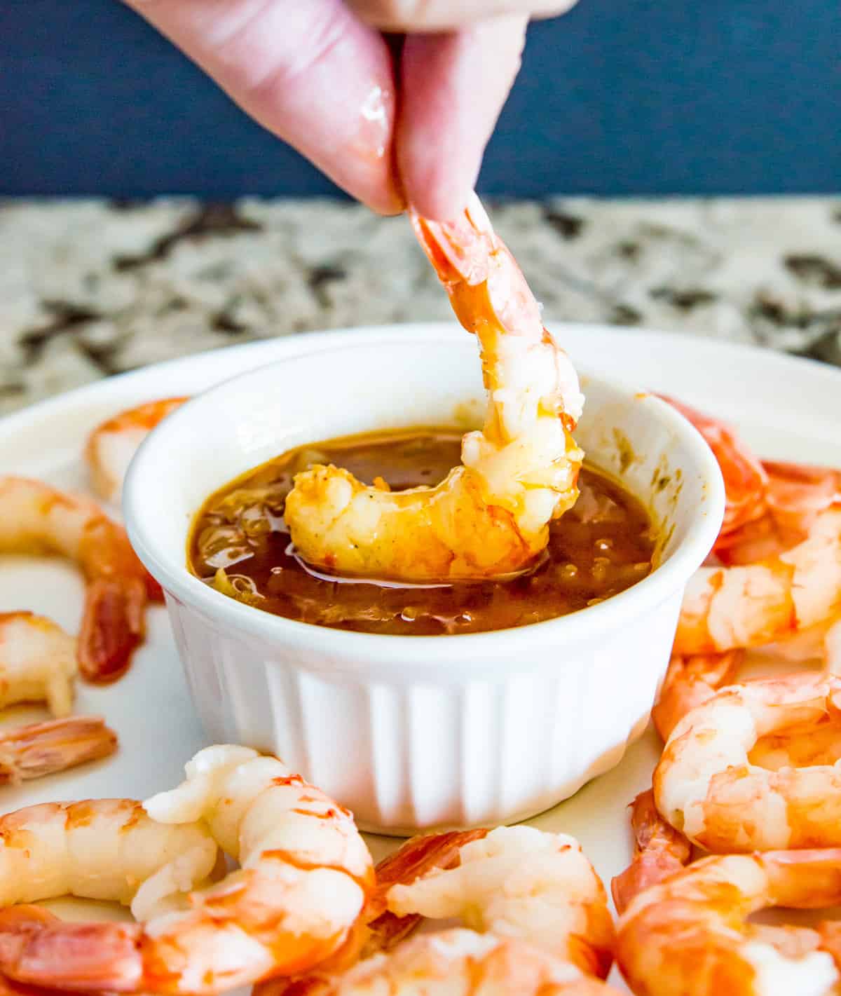 A shrimp being dipped in seafood butter sauce.