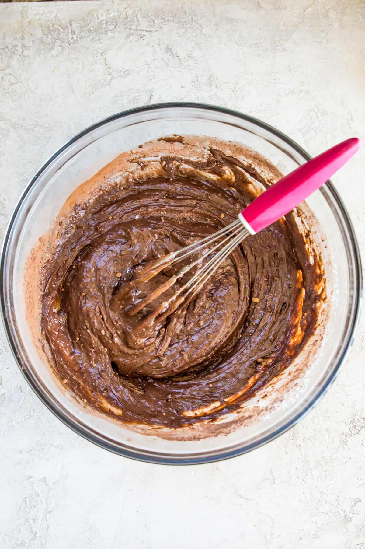 A glass bowl with a chocolate batter in it.