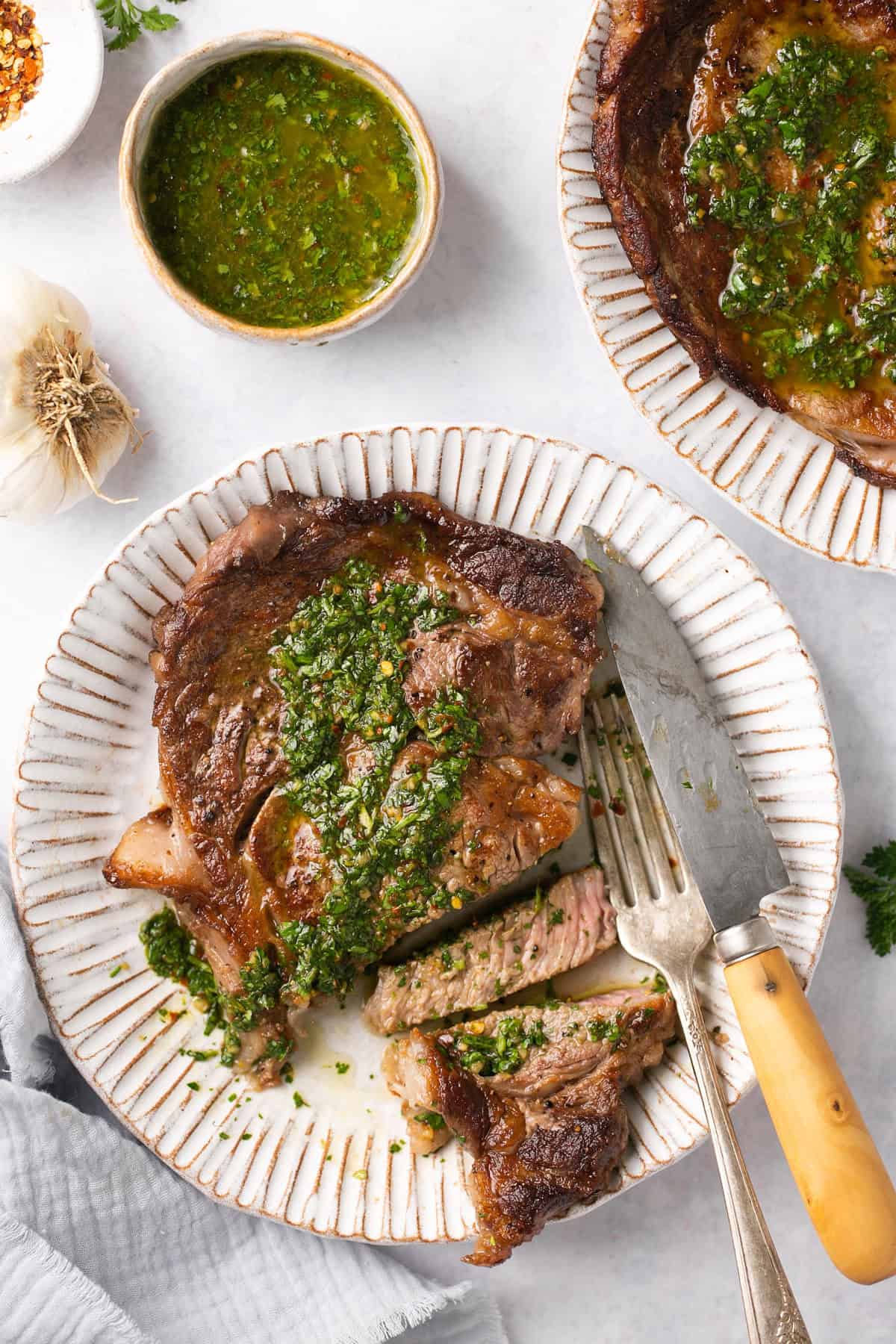 A cooked steak topped with chimichurri sauce.