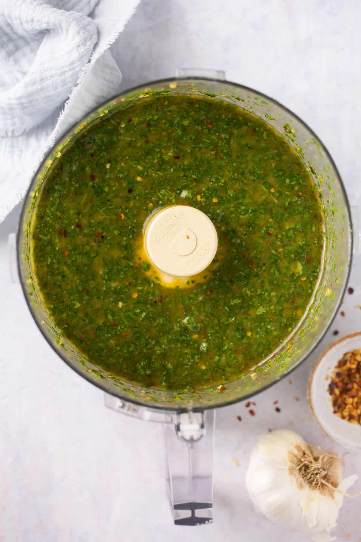 A food processor with a green sauce in it.