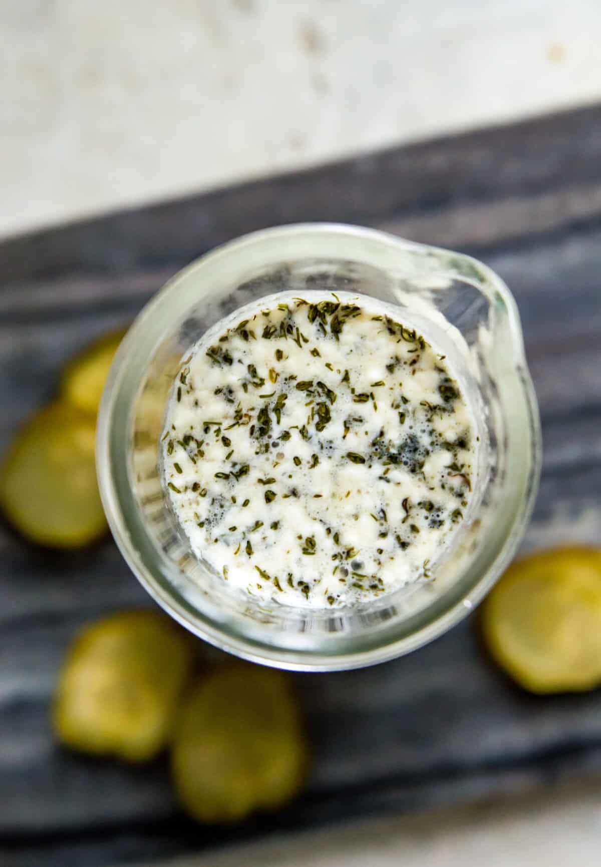 A jar of dill pickle salad dressing on a cutting board.