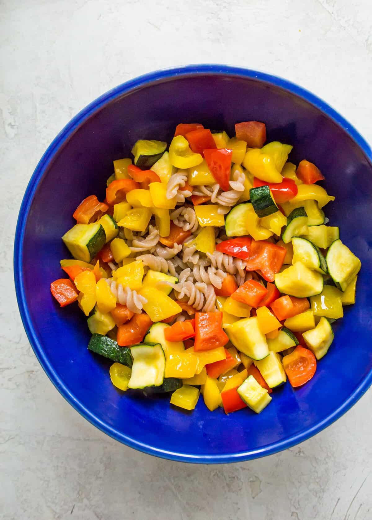 A bowl filled with cooked pasta noodles and cooked chopped bell peppers.