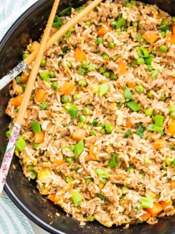 A pan filled with tuna fried rice with chop sticks on top.