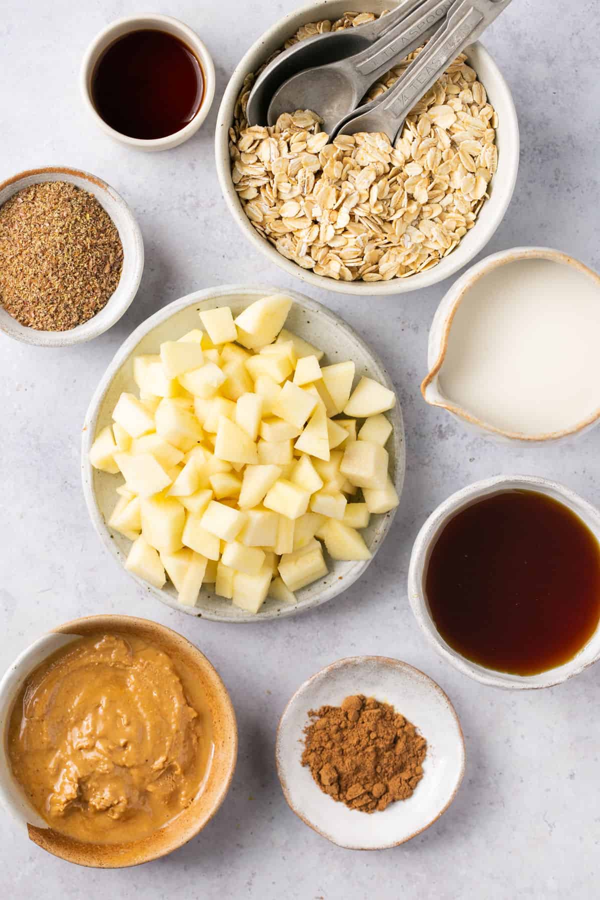 The ingredients needed to make overnight oats with apples all in small bowls. 