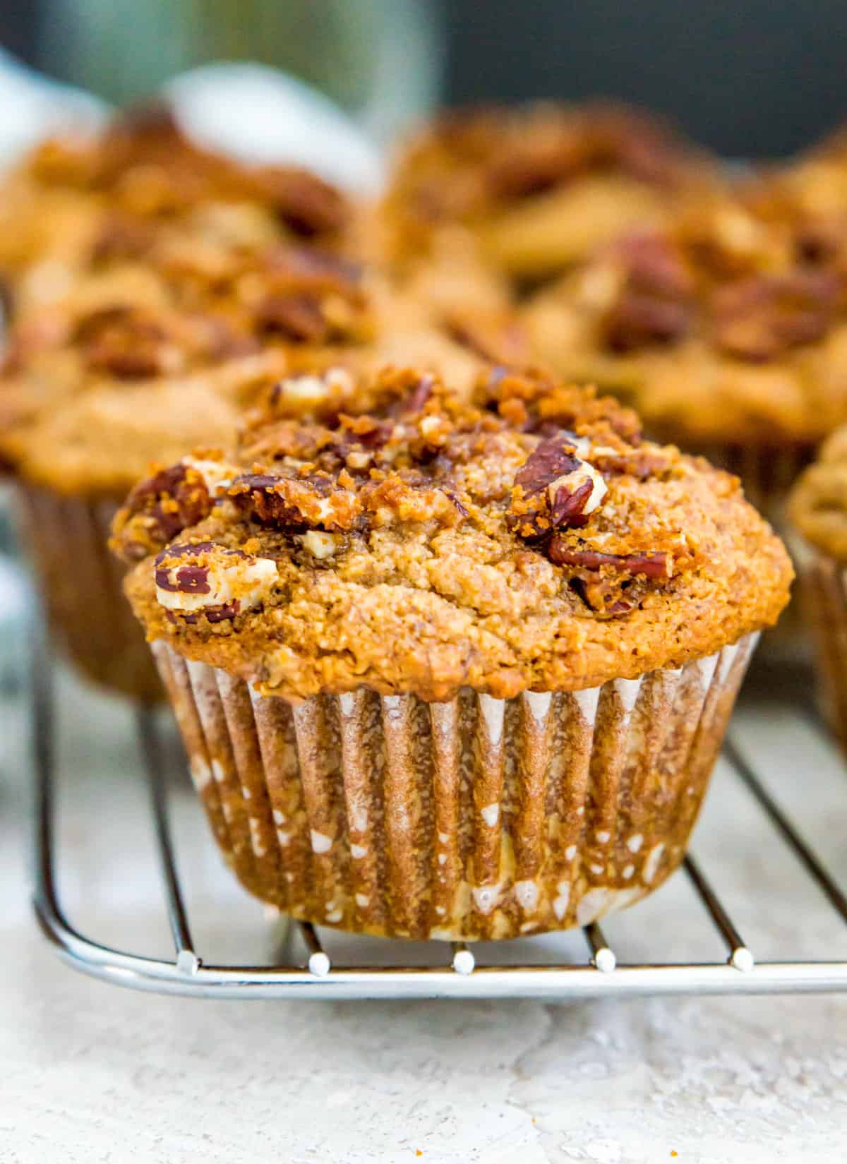 A banana pecan muffin with pecan streusel topping on a baking rack.