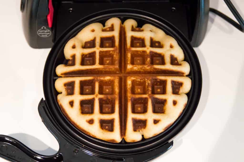 A waffle being cooked in a waffle maker. 