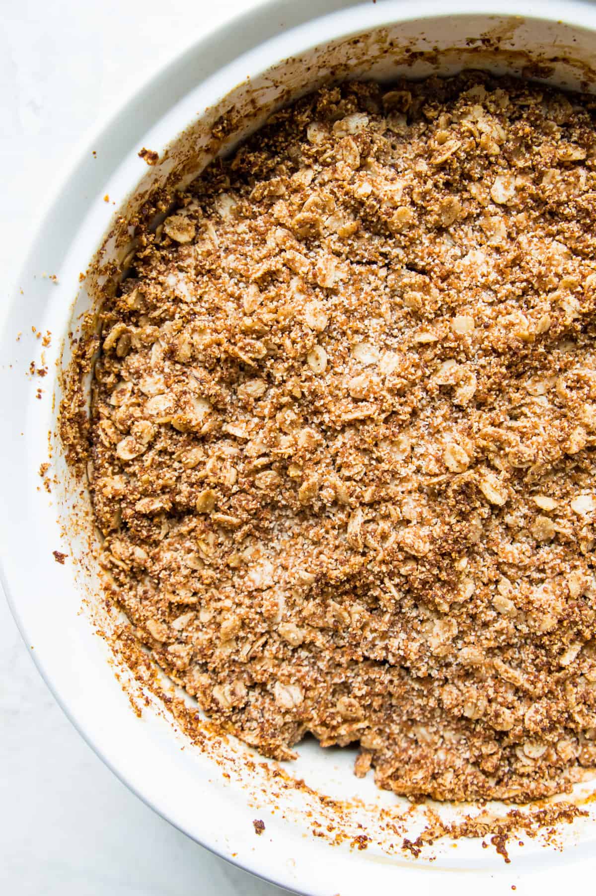 A cooked apple crumble in a white casserole dish.
