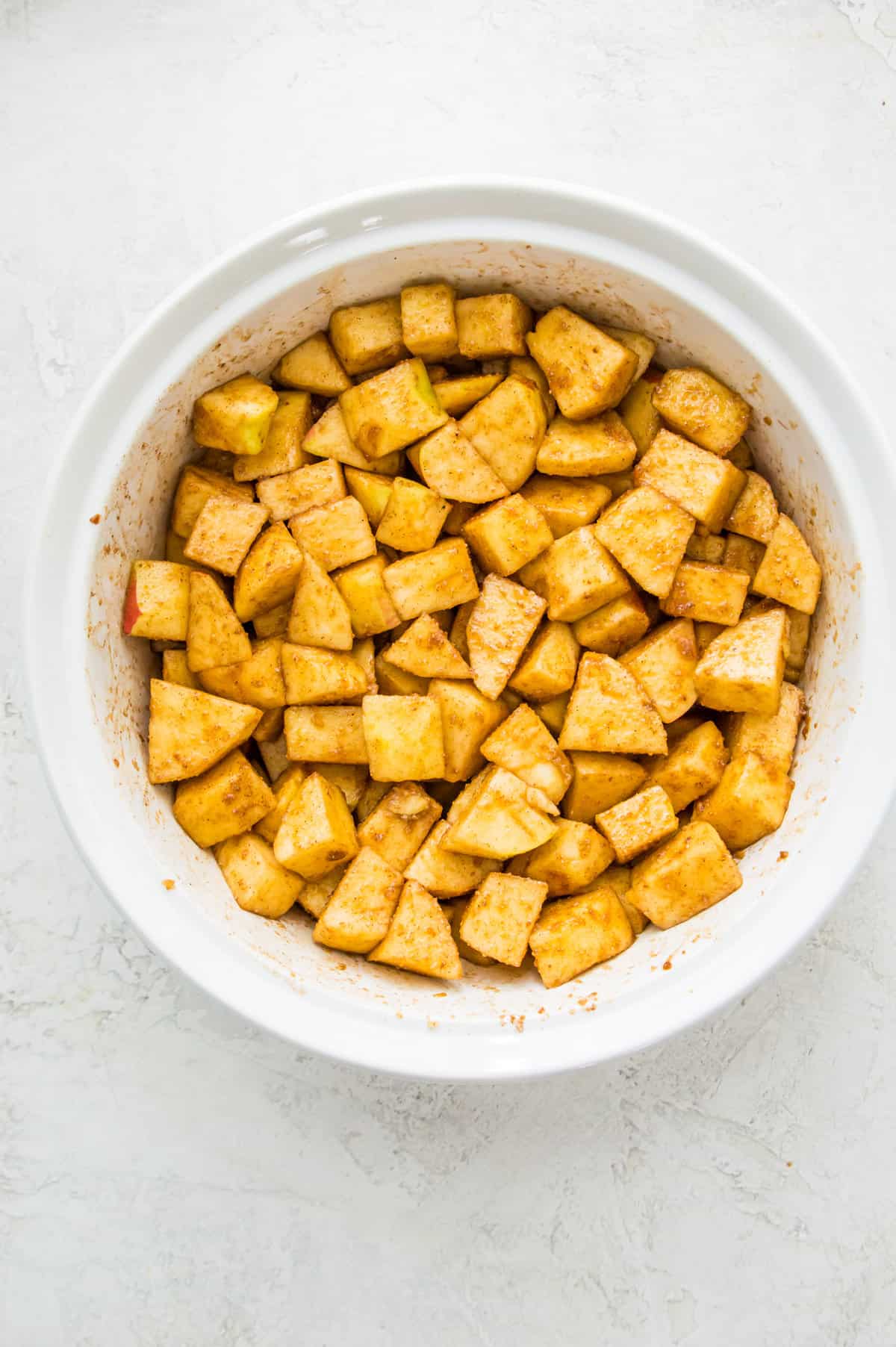 Peeled and chopped apples in a white casserole dish.