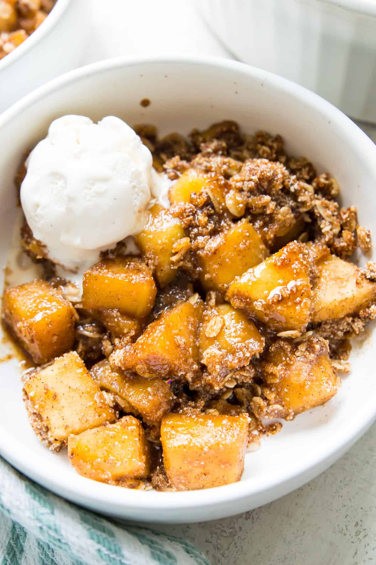 A bowl of healthy apple crumble with vanilla ice cream on top.