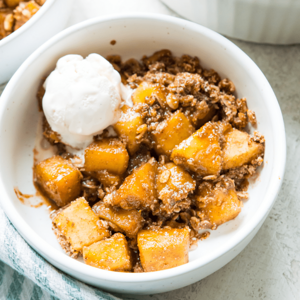 A bowl of healthy apple crumble with a scoop of vanilla ice cream on top.