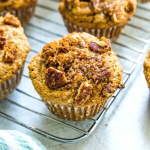 A batch of banana pecan muffins on a baking rack topped with a pecan streusel topping.