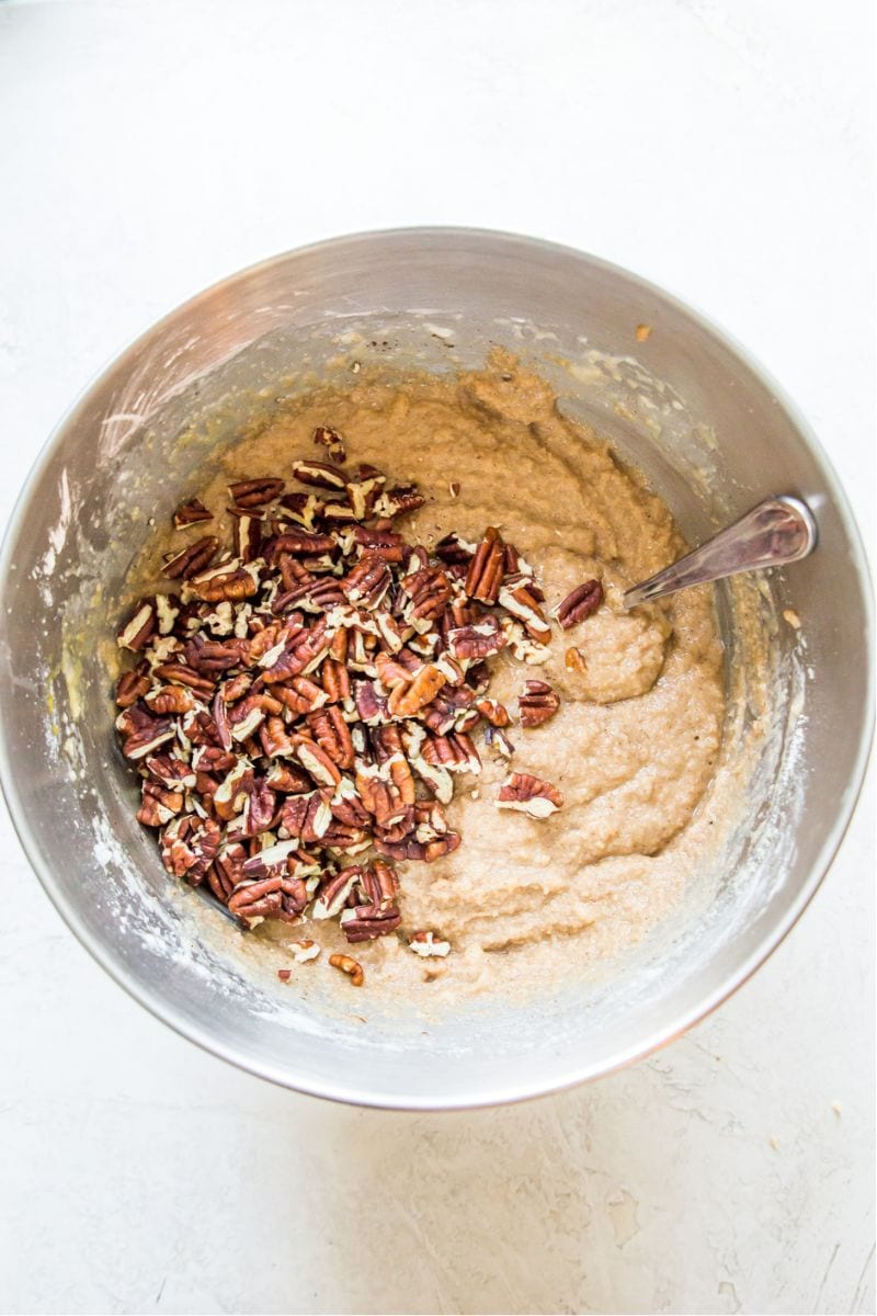 A mixing bowl filled with muffin batter and topped with pecan pieces.
