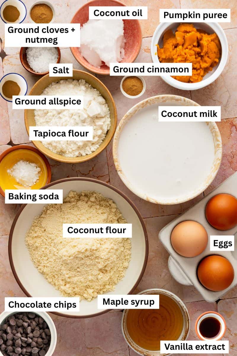 The ingredients needed for making pumpkin chocolate chip muffins separated into bowls including flour, milk, eggs, maple syrup, pumpkin puree and spices.
